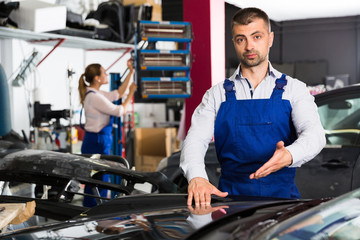 Male worker showing car after repainting