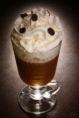 coffee drink with whipped cream in a glass on a dark table