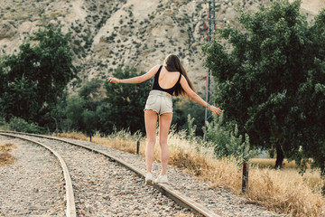 chica joven andando sobre vias de tren