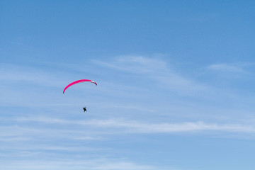 A red paraglider against a blue sky