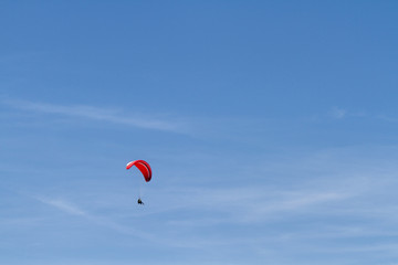 A red paraglider against a blue sky