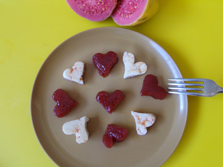 Brazilian dessert Romeo and Juliet, goiabada jam of guava and cheese Minas. Yelow background. And 2 sliced guavas composing the scene.