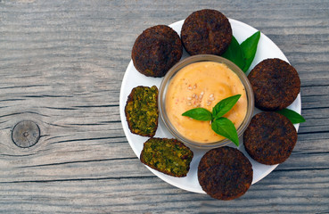 Freshly cooked falafel on a wooden table with tahini sauce.Eastern vegetarian meal of chickpea.