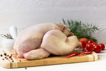 Raw chicken with tomatoes on a cutting board.