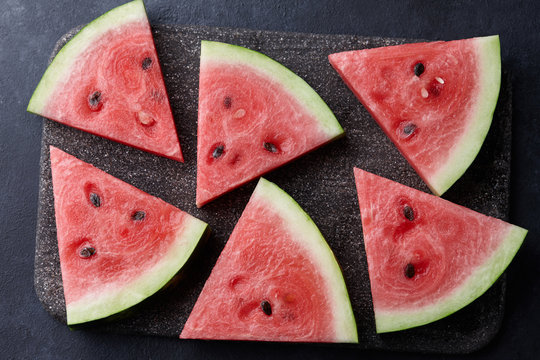 Fresh sliced watermelon on black stone background, top view