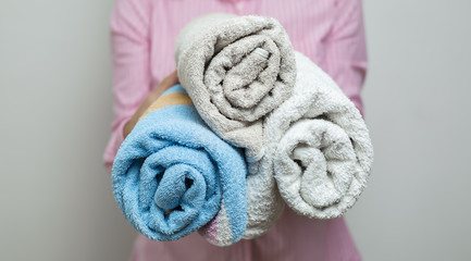 A woman is holding towels folded in a roll.  