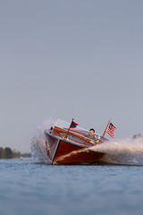 A vintage wooden powerboat throwing spray while turning.