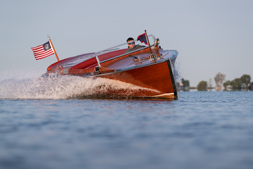 An antique, wood speedboat in a fast turn.