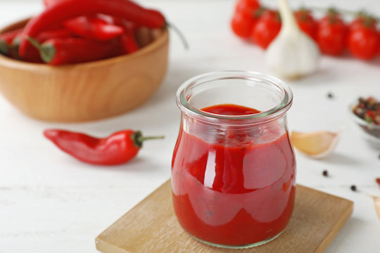 Jar with spicy chili sauce on light table