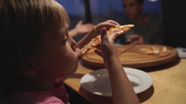 mom with children chooses pizza in a cafe and have a fun
