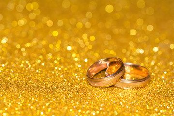 Wedding rings on a golden radiant background. Glitter shine.