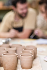 Two Ceramists Decorating Clay Crafts In workshop. Blurred Background