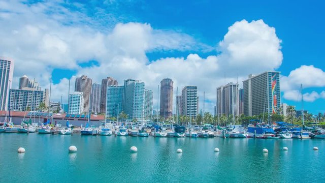 4K Cinematic urban time lapse in motion dynamic video view of the harbor with boats moored  and hotels in Honolulu Hawaii with dramatic clouds in the background