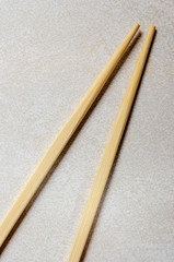 Two bamboo chopsticks  coming to a point on a gray patterned background
