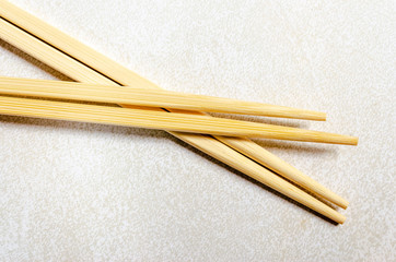 Two pair chopsticks  crossed on a gray patterned background