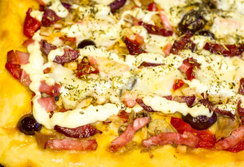 homemade pizza with peppers, plums, ham, sausage, cheese and spices, closeup