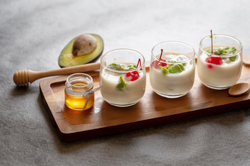 Glass of Cherry and avocado sliced in yogurt on wooden background