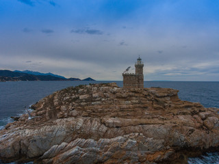 Fototapeta na wymiar A rock with a lighthouse near the coast of Italy.