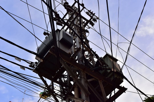 Large steel eletric support with a lot of tangled wires, cables. On the pole there is a step-down transformer. Complete confusion and mess