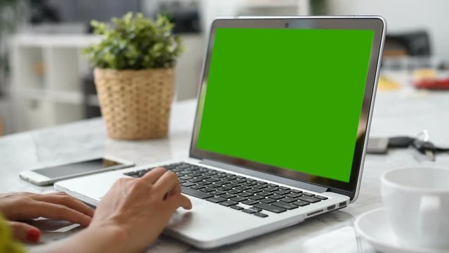 A laptop computer with a key green screen set on work office table.