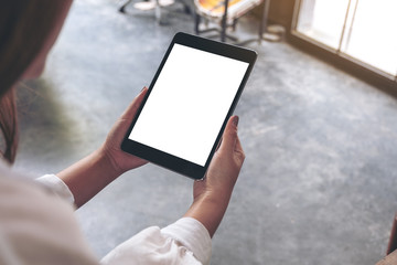 Top view mockup image of a woman sitting and holding black tablet pc with blank white desktop screen in cafe
