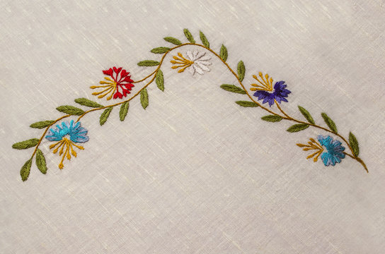 Corner with border of wildflowers on undulating  branches with  the cornflowers and leaves on a rough cotton fabric



