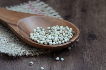 weiße Pfefferkörner auf einem Holzlöffel