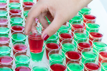 Junge Frau nimmt mit der Hand einen roten Jelly shot