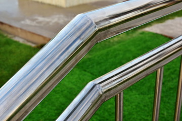 Detail of railing made of stainless steel. Close-up on a green background