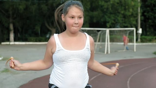 Little fat girl jumping rope in the stadium