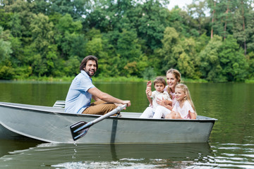 Side view of young family riding boat on lake at park