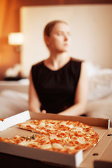 Obraz na płótnie Canvas Beautiful blonde hungry woman sitting on sofa and eating hot tasty pizza alone. Junk food. Diet. Calories.