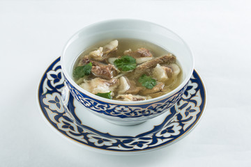 Meat soup served with herbs on decorative bowl over white background