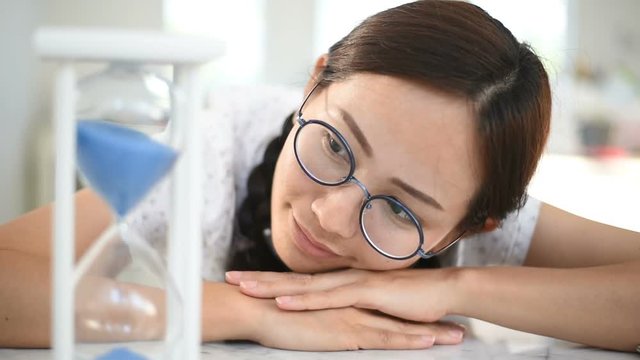 Young woman looking at hourglass in home