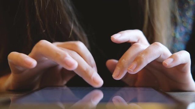 A woman using and typing at tablet pc screen in modern cafe