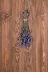 Dried flowers lavander, tied with a jute rope, hang on a  brown  wooden wall or fence