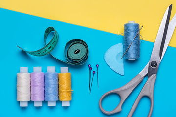 Scissors,  set of sewing needles and bright colored threads on  reels.