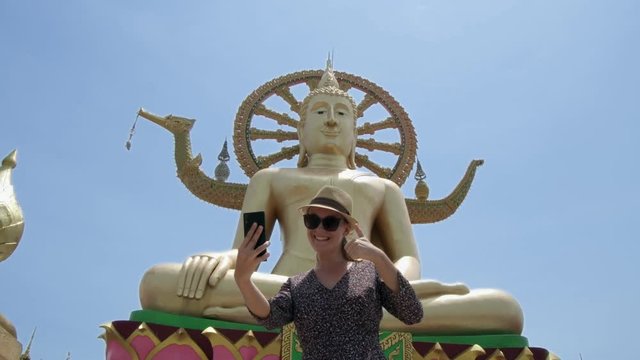 Young Caucasian Female Tourist Taking Selfie with Big Buddha Statue - Symbol and Main Landmark of Samui Island in Thailand. Tourism and Sightseeing