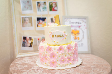 white, pink and golden one year birthday cake with flowers for a girl