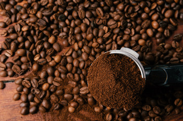 Some ground coffee on beans of coffee background on a wooden table. Close up, top view.