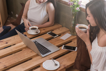 Two teenage women meet in coffee shop use smartphone and laptop play social media together in afternoon, life style of new teenager