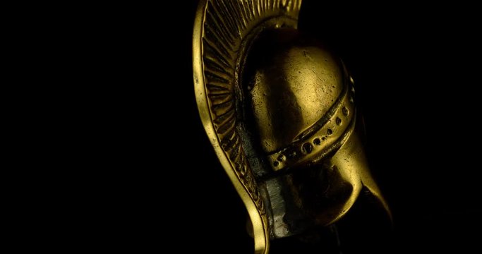 A wonderful golden Spartan helmet as part of the equipment of ancient greek soldiers. King Leonidas and his 300th The piece of metal stands against a black background