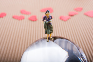 Woman figurine on half a globe with paper hearts