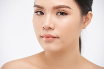 Young pretty Asian woman with clear skin looking at camera on white background