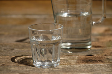 Wasserglas mit Kanten, Kanne im Hintergrund