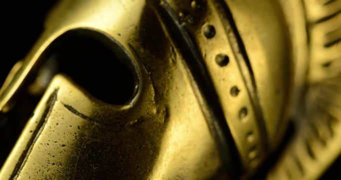 A wonderful golden Spartan helmet as part of the equipment of ancient greek soldiers. King Leonidas and his 300th The piece of metal stands against a black background