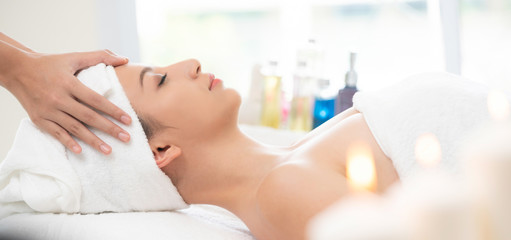 Relaxed woman gets facial and head massage in spa.