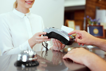 Guest at hotel reception paying with check during check-in