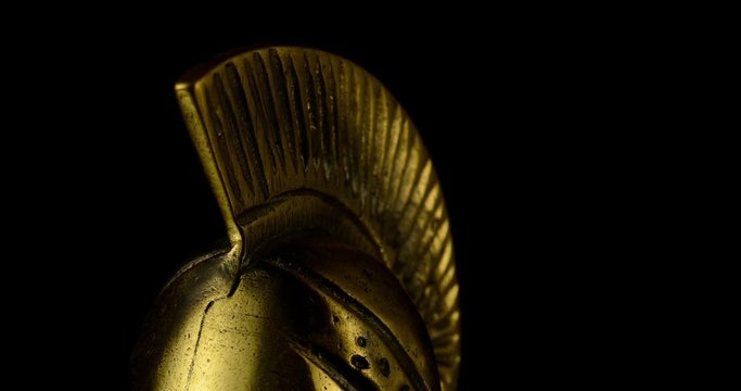 A wonderful golden Spartan helmet as part of the equipment of ancient greek soldiers. King Leonidas and his 300th The piece of metal stands against a black background