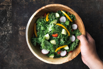 Kale salad in wooden bowl on rustic background